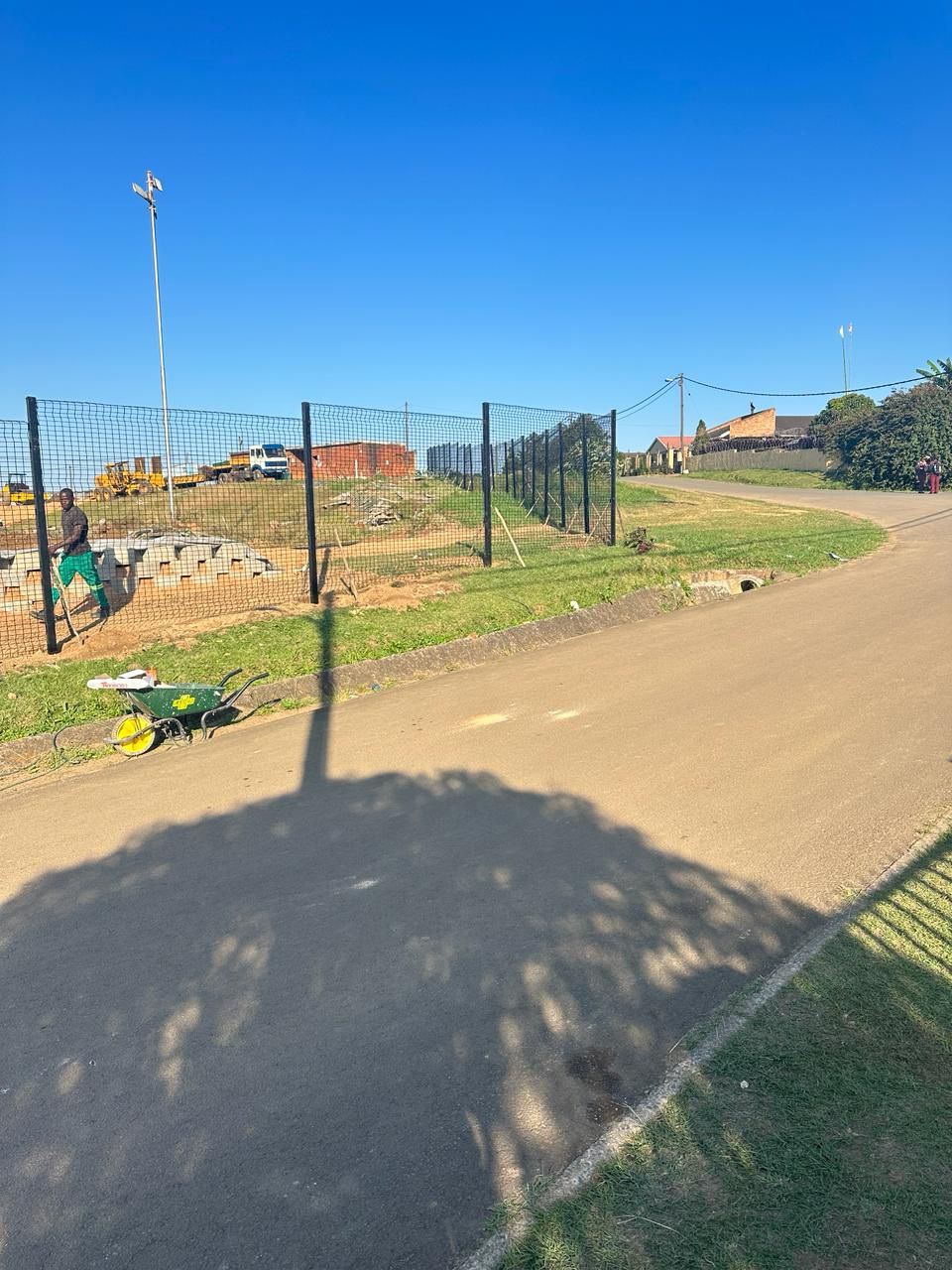 Mesh perimeter fence along an access road at a sports ground
